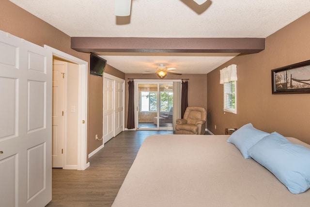 bedroom with a textured ceiling, beamed ceiling, dark hardwood / wood-style floors, access to exterior, and ceiling fan