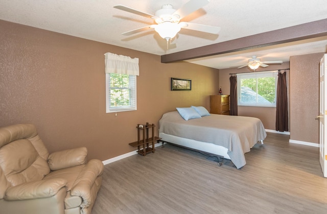 bedroom with wood-type flooring, ceiling fan, and beamed ceiling