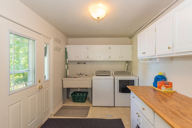 washroom with cabinets, a textured ceiling, sink, and washing machine and clothes dryer