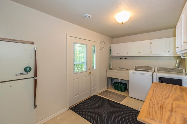 laundry area with cabinets, a textured ceiling, and washer and dryer