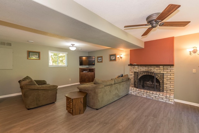 living room featuring ceiling fan, a fireplace, and dark hardwood / wood-style flooring