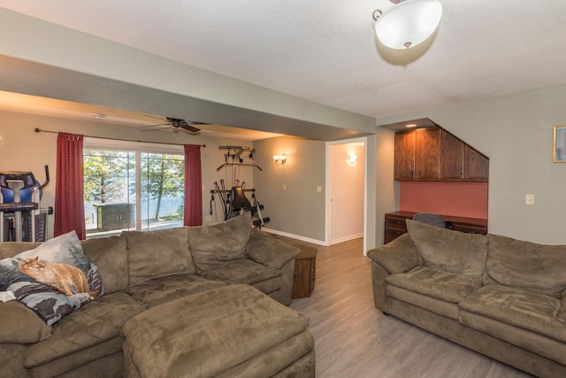 living room featuring ceiling fan, a textured ceiling, and light hardwood / wood-style floors