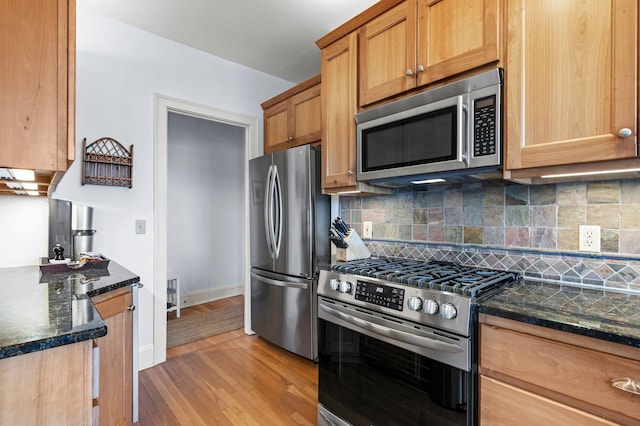 kitchen featuring dark stone counters, light hardwood / wood-style flooring, stainless steel appliances, and tasteful backsplash