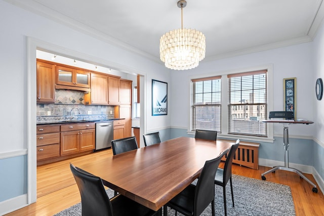 dining room with crown molding, sink, light hardwood / wood-style flooring, and a chandelier