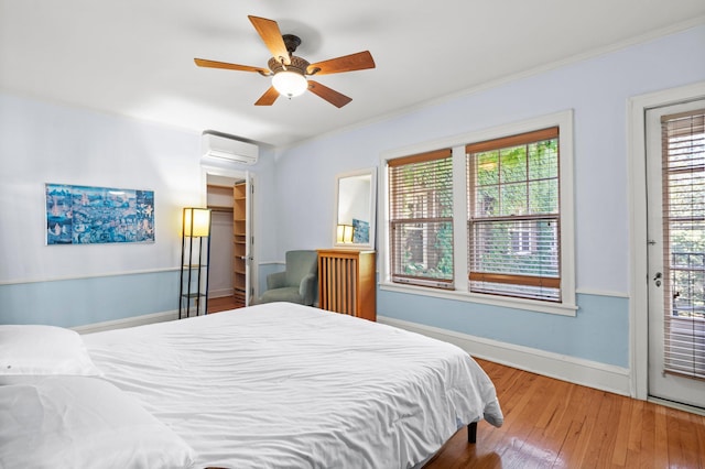 bedroom with ceiling fan, ornamental molding, access to exterior, hardwood / wood-style floors, and an AC wall unit