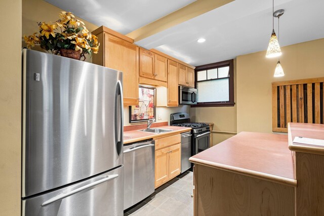 kitchen featuring light brown cabinetry, decorative light fixtures, appliances with stainless steel finishes, and sink