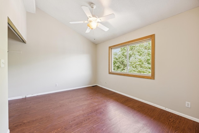 spare room with dark hardwood / wood-style floors, vaulted ceiling, and ceiling fan