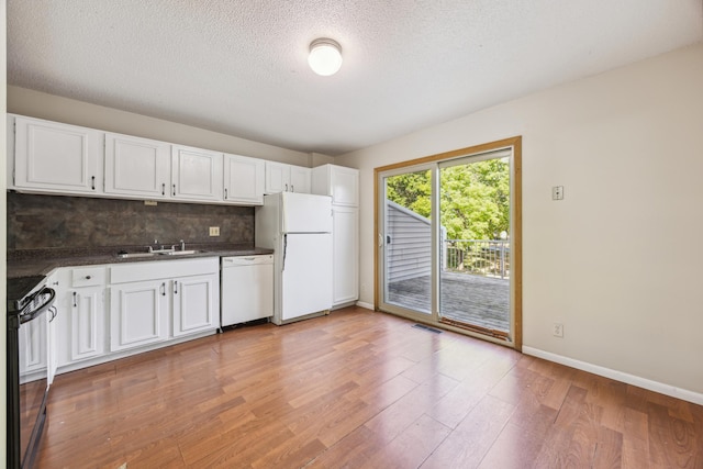 kitchen with light wood-type flooring, white appliances, sink, decorative backsplash, and white cabinetry