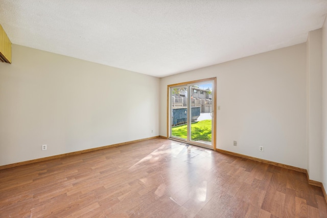 spare room featuring a textured ceiling and light wood-type flooring