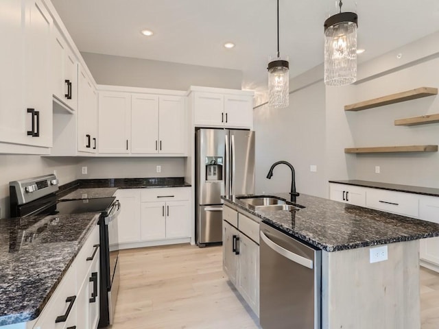 kitchen with sink, white cabinetry, hanging light fixtures, stainless steel appliances, and a center island with sink