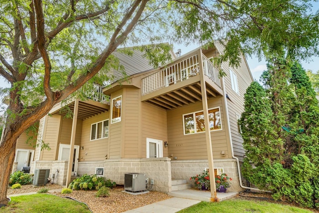 rear view of property featuring central AC unit and a balcony