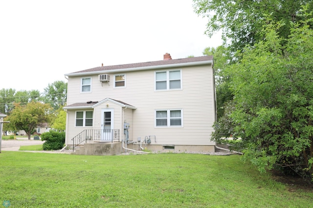 rear view of house featuring a wall unit AC and a lawn