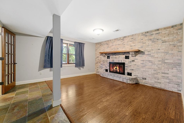 unfurnished living room with a brick fireplace, dark hardwood / wood-style floors, and brick wall