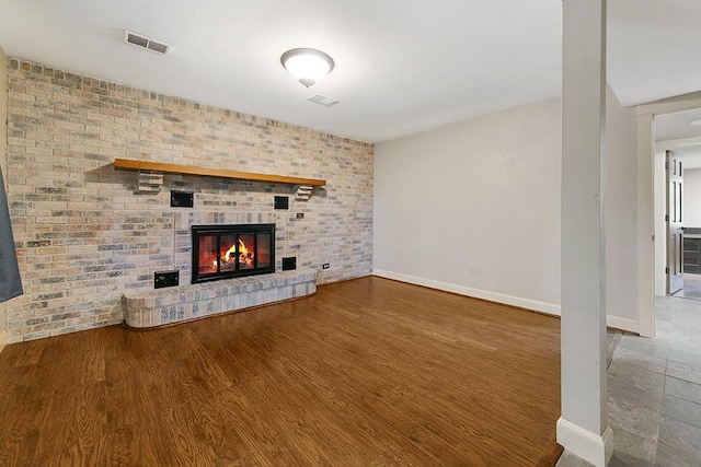 unfurnished living room featuring brick wall and hardwood / wood-style floors