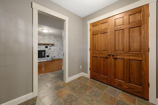 foyer entrance featuring a brick fireplace and dark hardwood / wood-style flooring