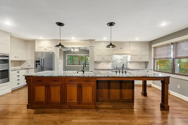 kitchen featuring a kitchen island with sink, sink, dark hardwood / wood-style flooring, pendant lighting, and appliances with stainless steel finishes