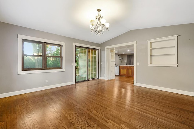 unfurnished room featuring vaulted ceiling, hardwood / wood-style floors, an inviting chandelier, and sink