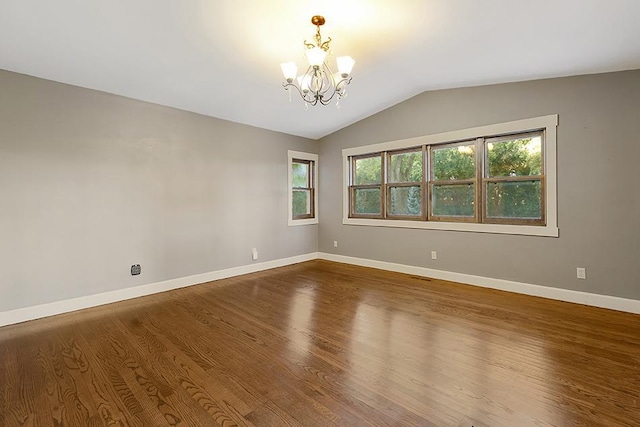 unfurnished room with hardwood / wood-style flooring, lofted ceiling, and a chandelier