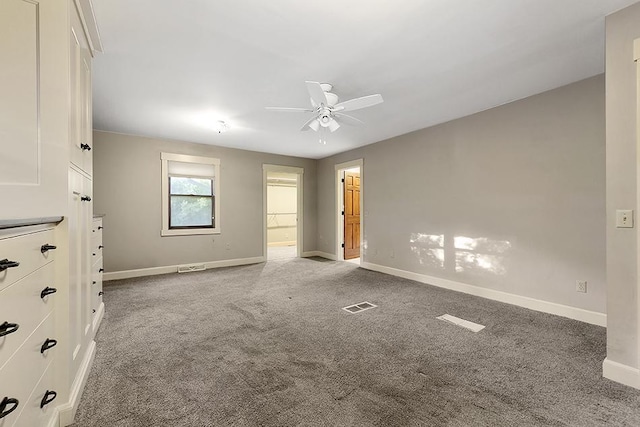 unfurnished bedroom with light carpet, a spacious closet, and ceiling fan