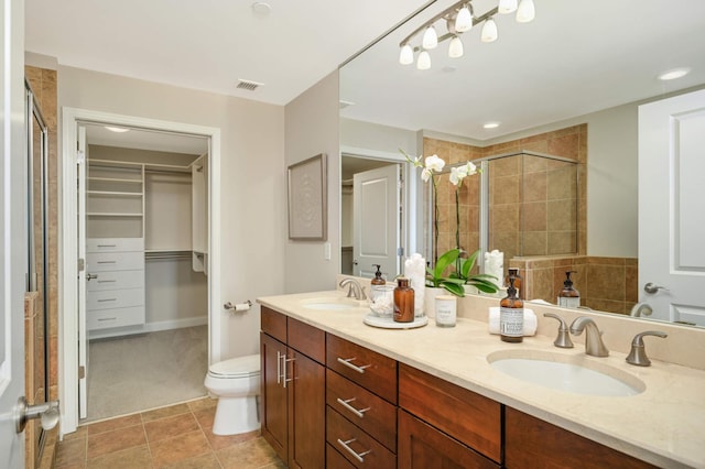 bathroom with tile patterned floors, an enclosed shower, vanity, and toilet