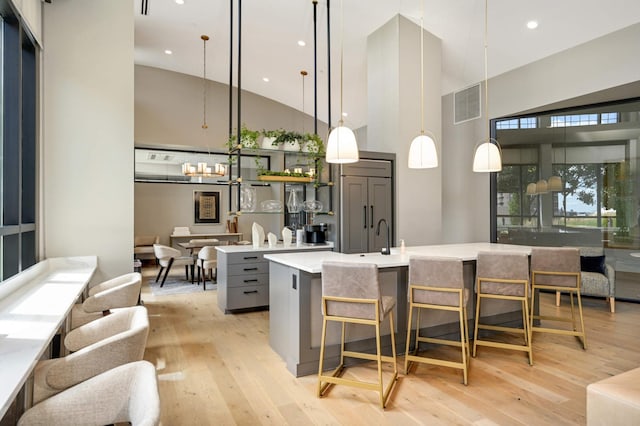 kitchen with light hardwood / wood-style floors, pendant lighting, gray cabinets, and high vaulted ceiling