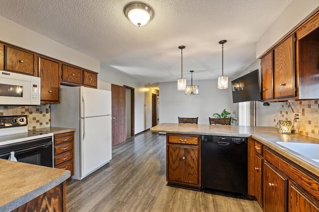 kitchen featuring a peninsula, backsplash, dark wood-style floors, black appliances, and decorative light fixtures