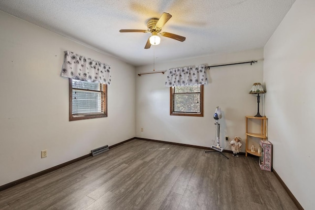 empty room featuring a textured ceiling, baseboards, and wood finished floors