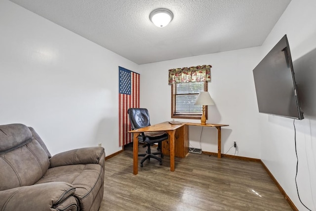 home office featuring a textured ceiling, baseboards, and wood finished floors