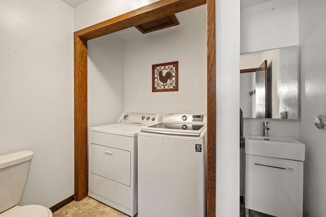 washroom with a sink, laundry area, washing machine and clothes dryer, and baseboards