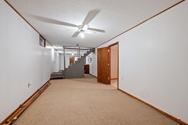 spare room with light colored carpet, stairway, ceiling fan, a textured ceiling, and baseboards