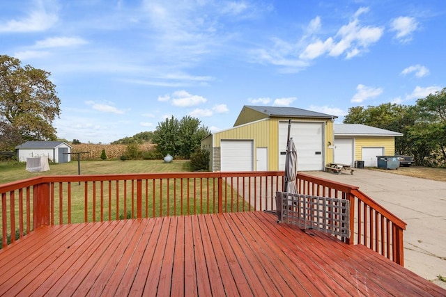 wooden deck featuring a yard, a detached garage, and an outbuilding