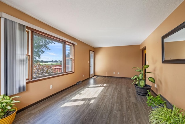 spare room featuring a textured ceiling, wood finished floors, and baseboards