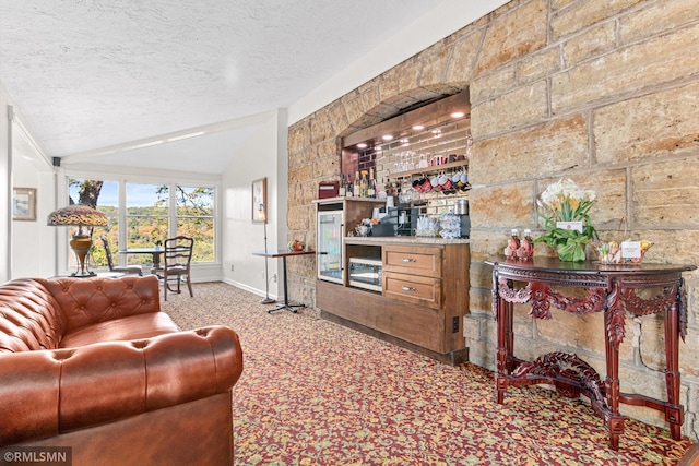 carpeted living room featuring vaulted ceiling, a textured ceiling, and bar