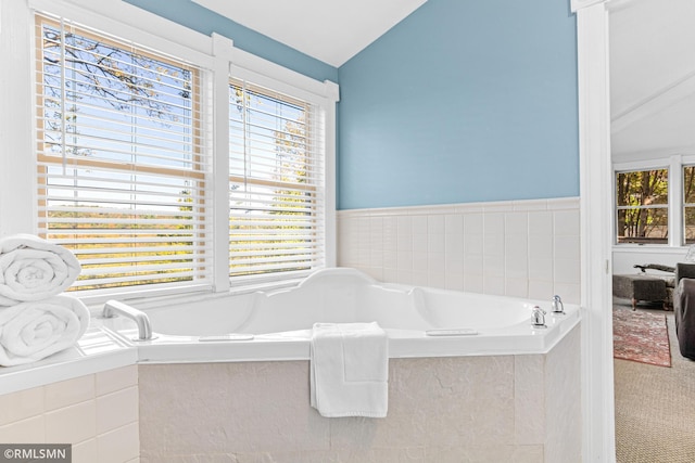 bathroom with ornamental molding, tiled bath, and vaulted ceiling