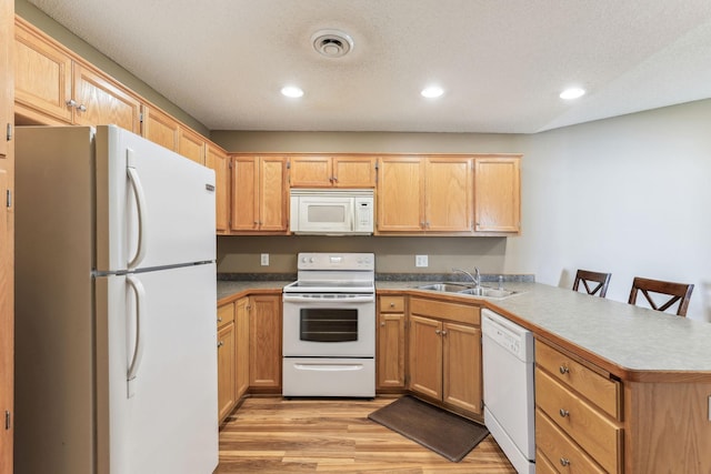 kitchen featuring a kitchen breakfast bar, light hardwood / wood-style floors, white appliances, kitchen peninsula, and sink