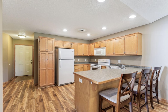 kitchen featuring white appliances, kitchen peninsula, a textured ceiling, wood-type flooring, and sink