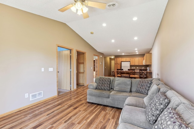 living room with ceiling fan, lofted ceiling, and light hardwood / wood-style floors