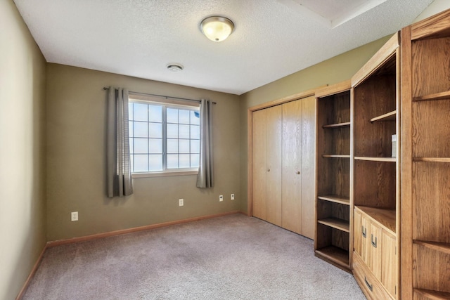 unfurnished bedroom featuring light colored carpet, a textured ceiling, and a closet