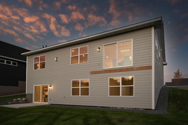 back house at dusk featuring a yard