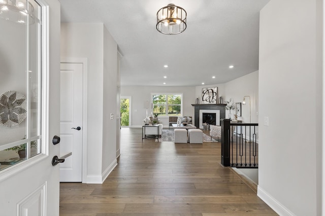 entrance foyer featuring wood-type flooring, a fireplace, and an inviting chandelier