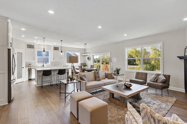 living room featuring light wood-type flooring, a textured ceiling, and sink