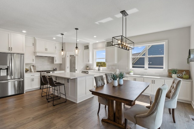 dining area with a textured ceiling, dark hardwood / wood-style flooring, sink, and a notable chandelier