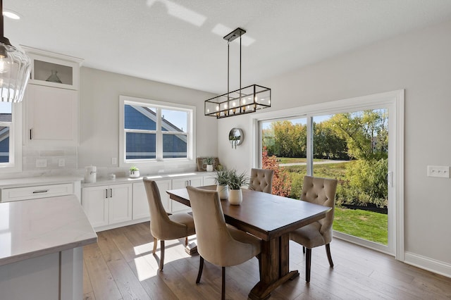 dining room featuring light wood-type flooring, a textured ceiling, a chandelier, and plenty of natural light