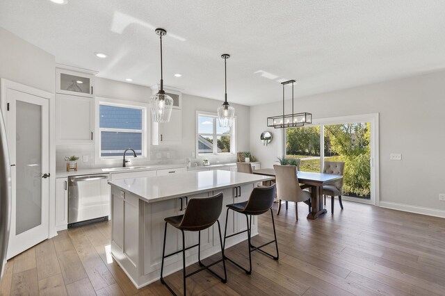 kitchen with white cabinets, dishwasher, a center island, and a healthy amount of sunlight