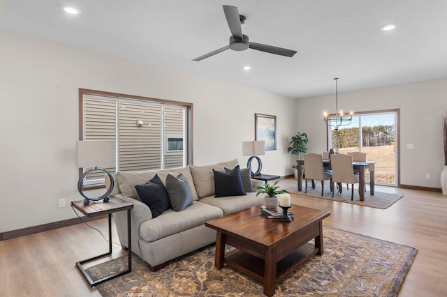 living room featuring wood-type flooring and ceiling fan with notable chandelier