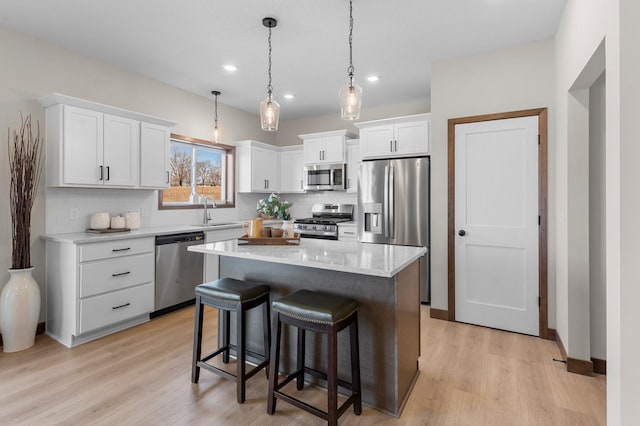 kitchen featuring sink, appliances with stainless steel finishes, hanging light fixtures, a center island, and white cabinets