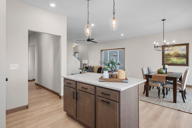 kitchen with pendant lighting, a kitchen island, and light hardwood / wood-style flooring