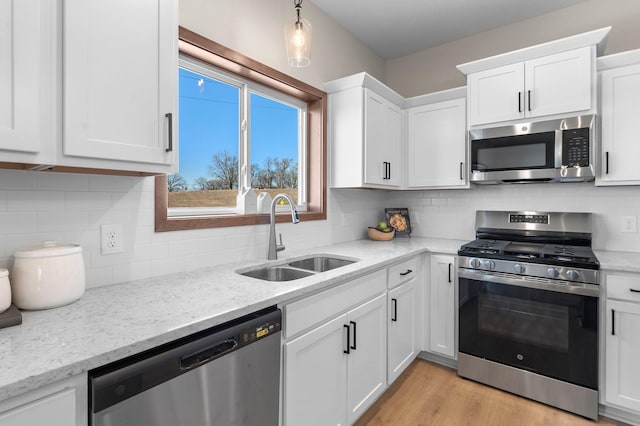 kitchen with sink, stainless steel appliances, white cabinets, and light wood-type flooring