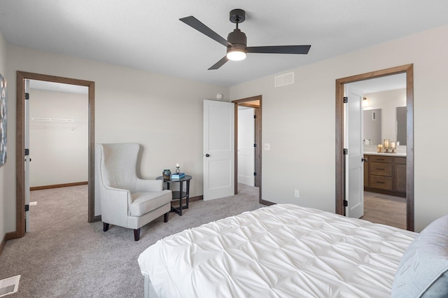 carpeted bedroom featuring a spacious closet, a closet, ceiling fan, and ensuite bathroom