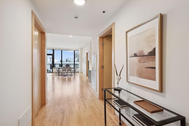 hallway with a wall of windows and light hardwood / wood-style flooring